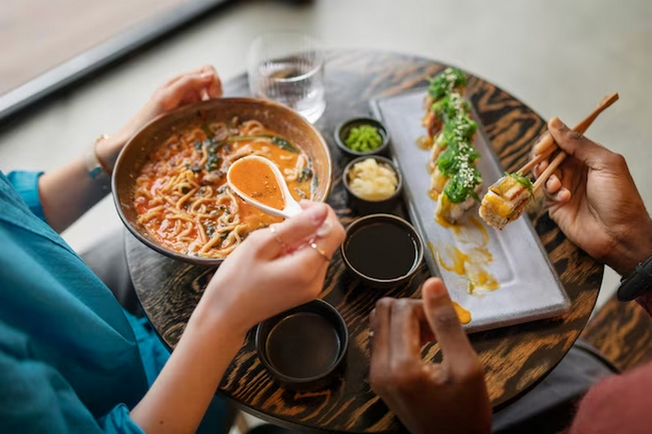 Two individuals enjoying ramen while another person is savoring maki